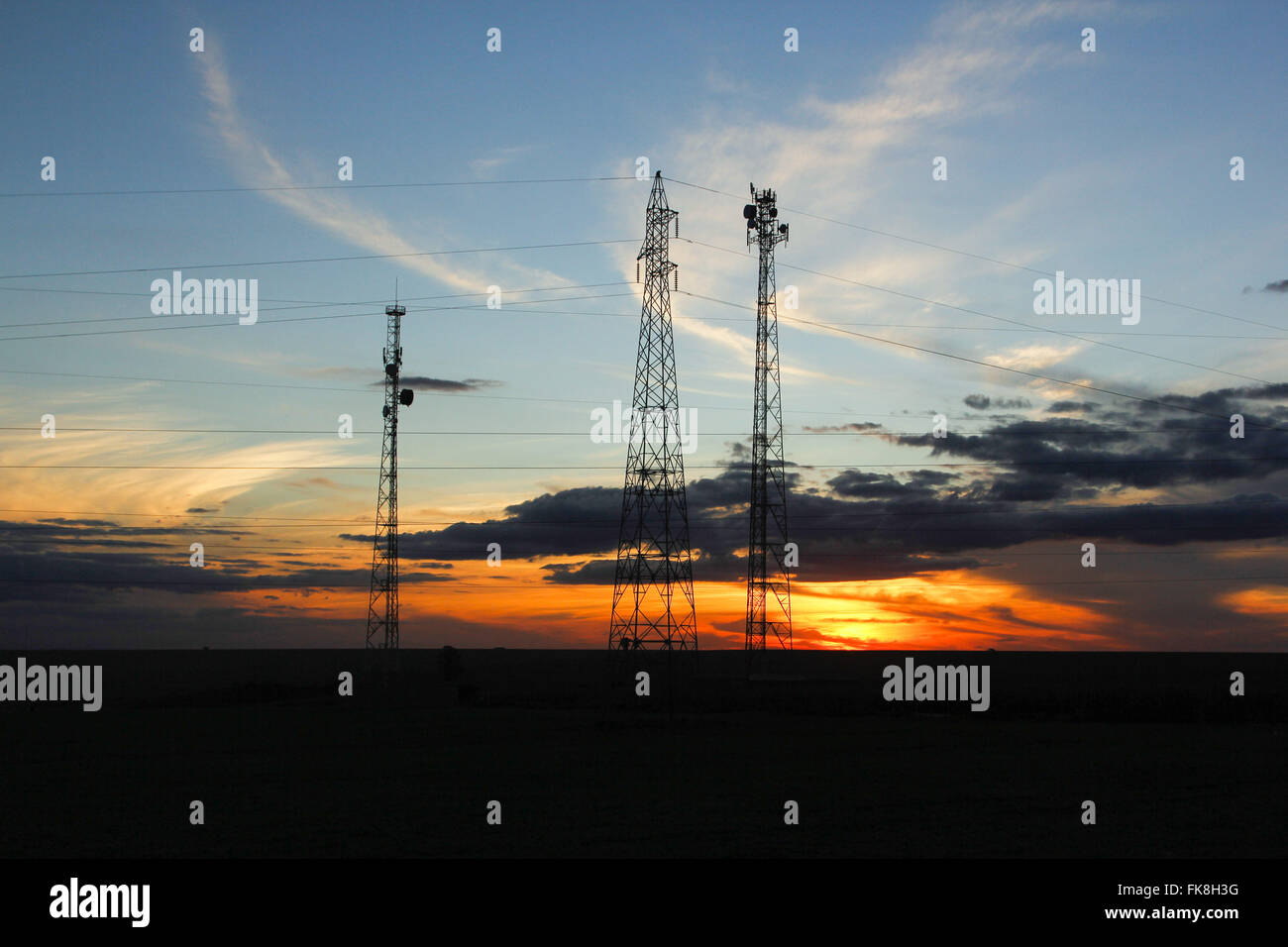 Le torri di trasmissione di energia elettrica e di telecomunicazioni nel tardo pomeriggio Foto Stock