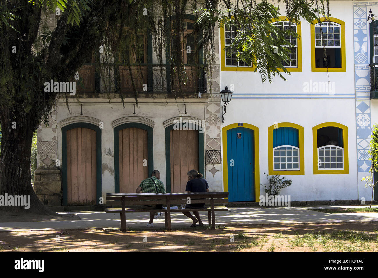 La gente seduta su una panchina nel parco matrice e case coloniali in centro storico Foto Stock