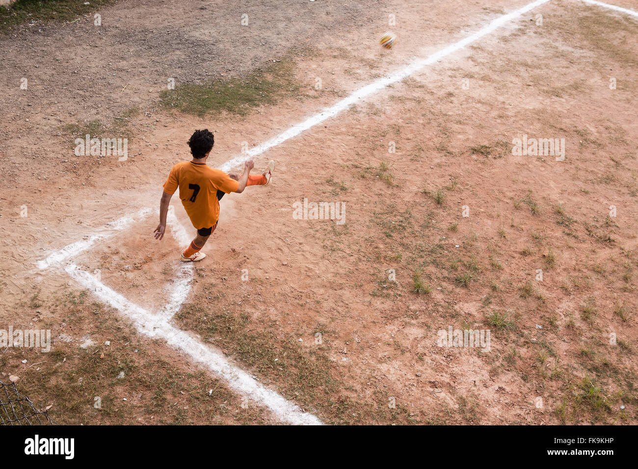 Giocatore di calcio calciare il pallone in floodplain calcio d'angolo Foto Stock