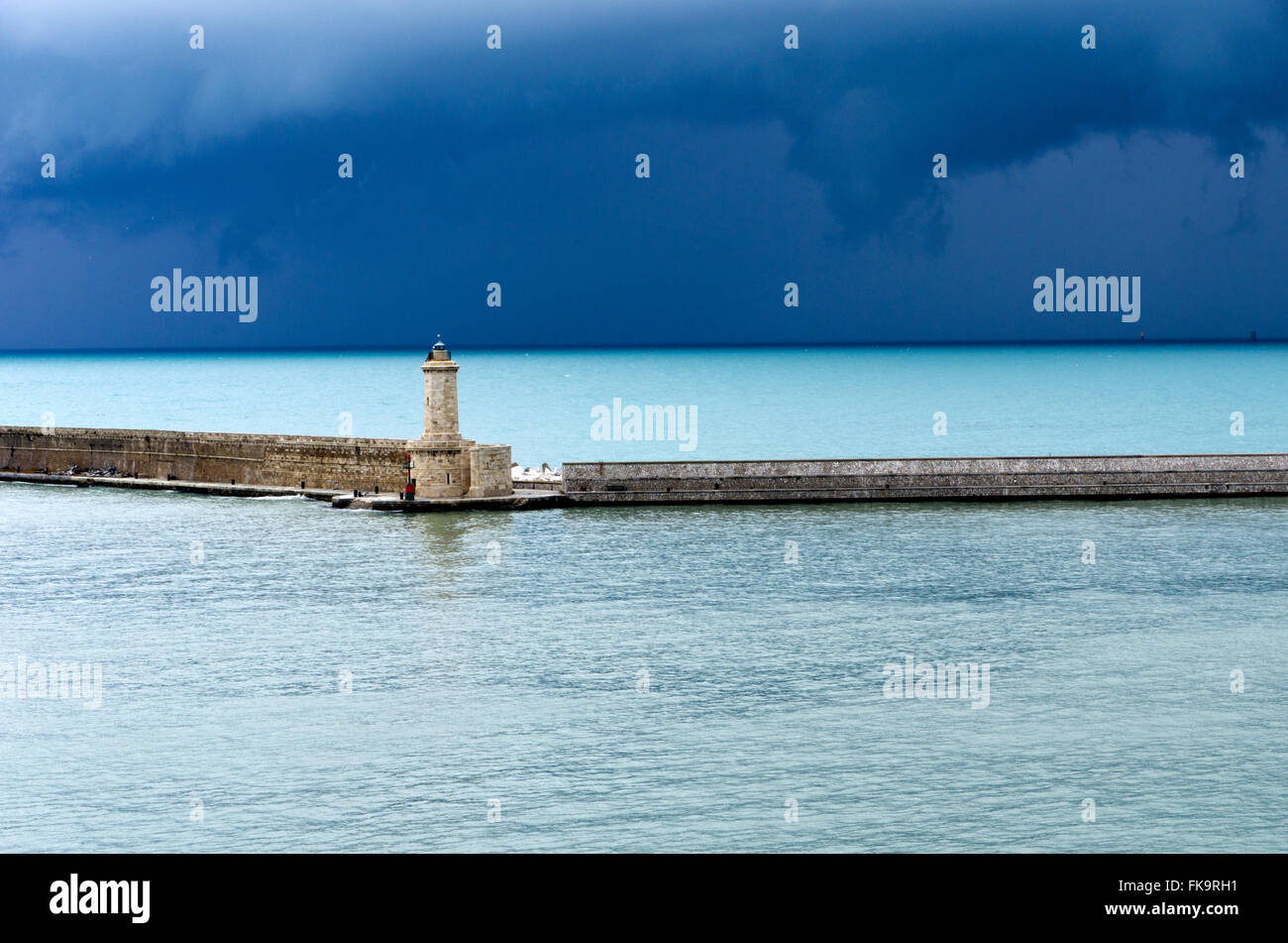 Porto commerciale seawall, luce di navigazione e molto dark sky all'orizzonte. Foto Stock