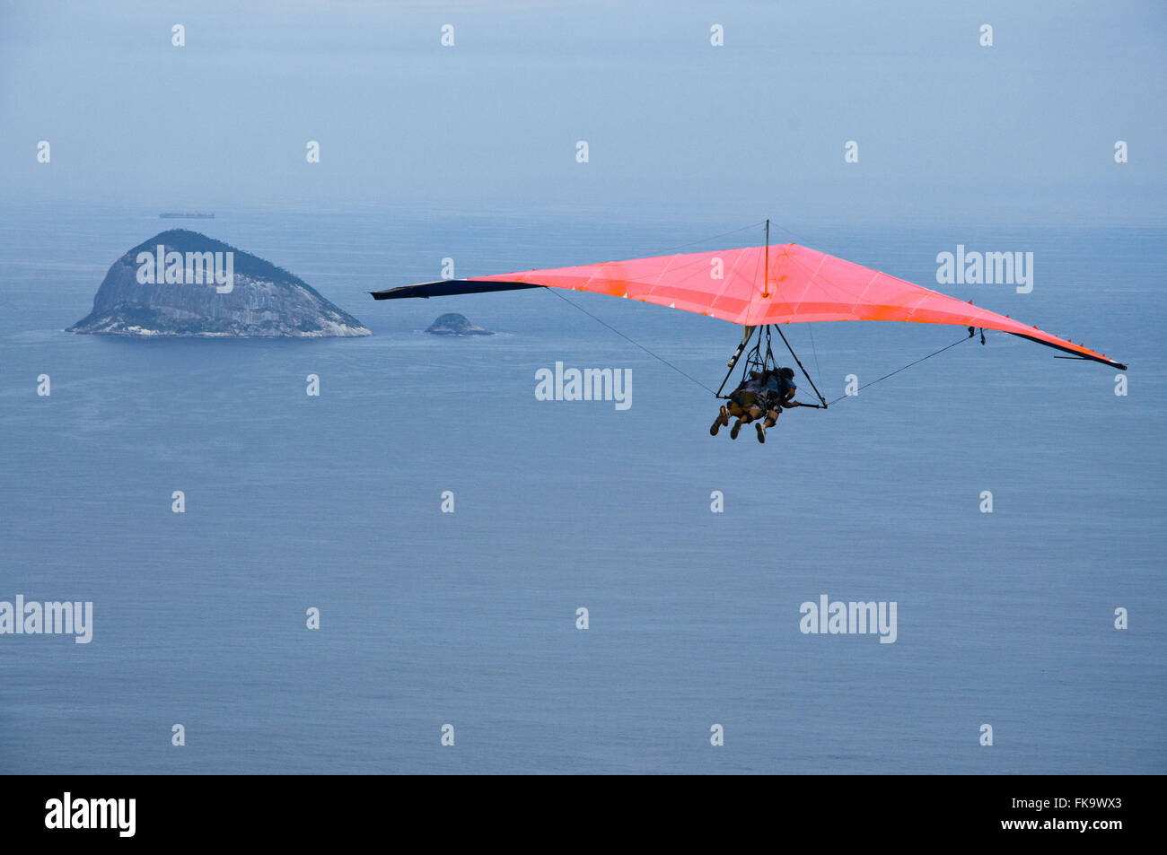 Deltaplano volare sopra la spiaggia di Sao Conrado con formazione di roccia in background Foto Stock