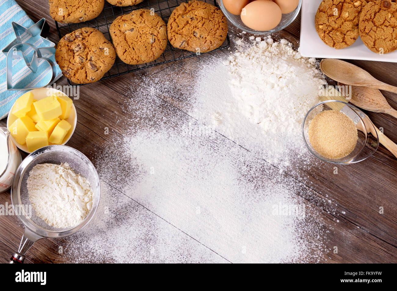 Appena sfornati i biscotti al cioccolato al buio su un tavolo di legno con spolverata di farina e ingredienti. Foto Stock