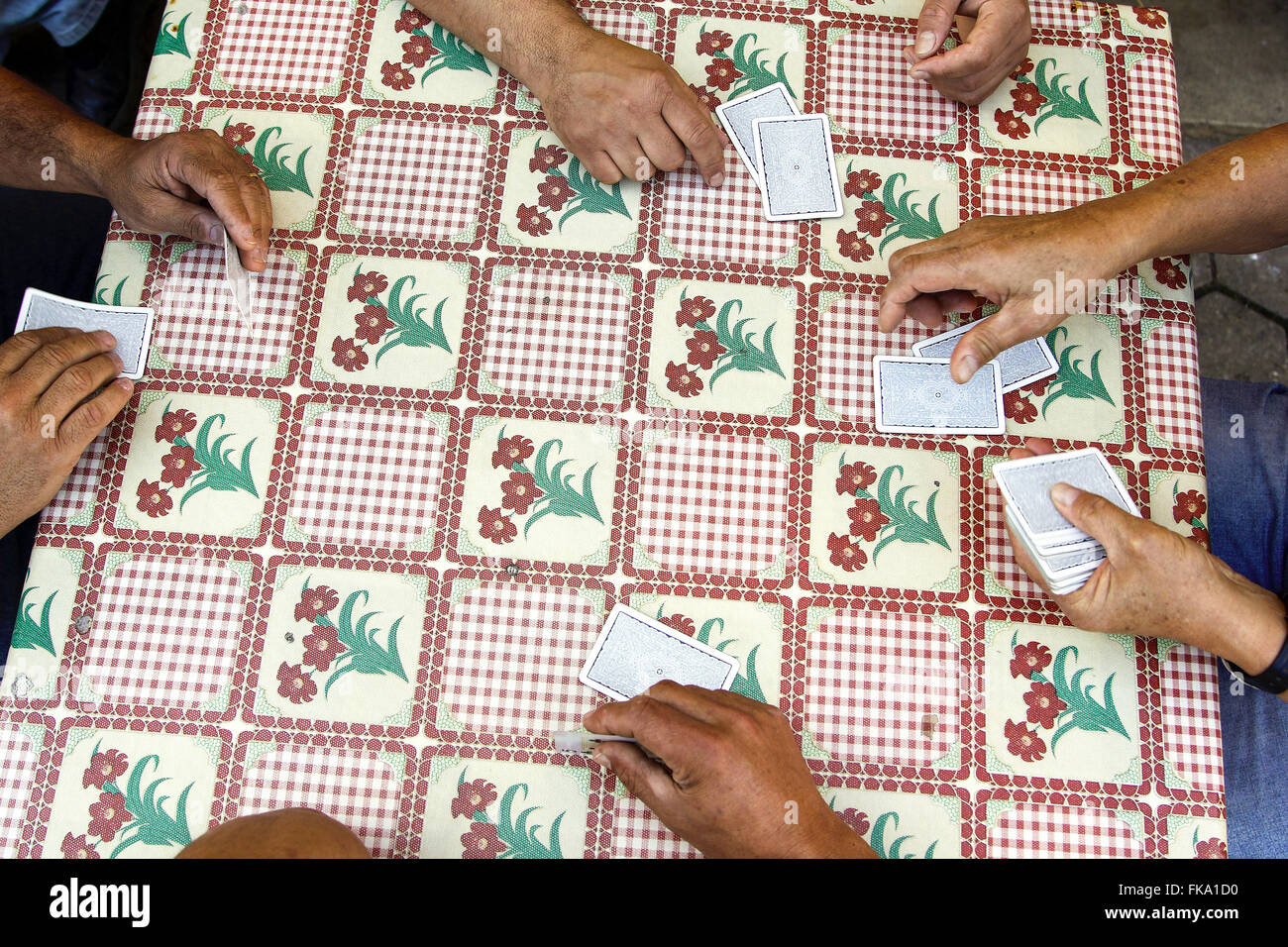 Carte da gioco sul tavolo con tovaglia in plastica florida Foto Stock