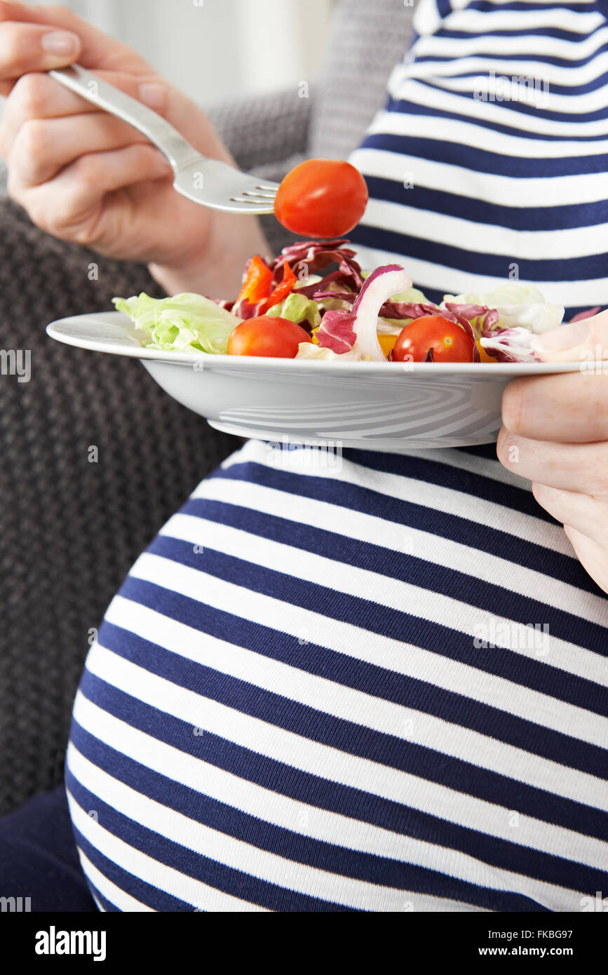 Close up della donna incinta mangiare insalata sana Foto Stock