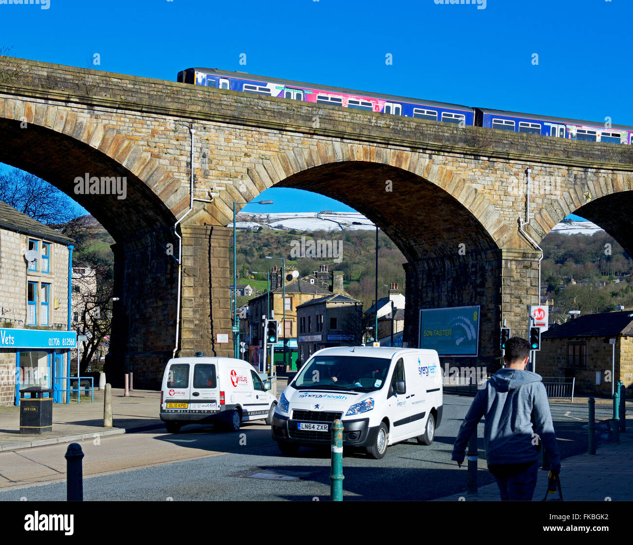 Treno sul viadotto ferroviario e il traffico nella strada, Todmorden, West Yorkshire, Inghilterra, Regno Unito Foto Stock