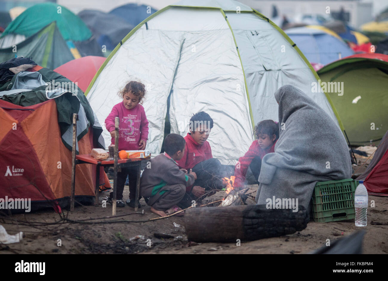 Idomeni, Grecia. 08 Mar, 2016. I rifugiati si sono riuniti intorno ad un fuoco davanti alla loro tenda dopo forti piogge nel campo profughi al confine Greek-Macedonian vicino Idomeni, Grecia, 08 marzo 2016. Solo pochi rifugiati dalla Siria e Iraq sono ammessi a croce in Macedonia ogni giorno. Foto: KAY NIETFELD/dpa/Alamy Live News Foto Stock