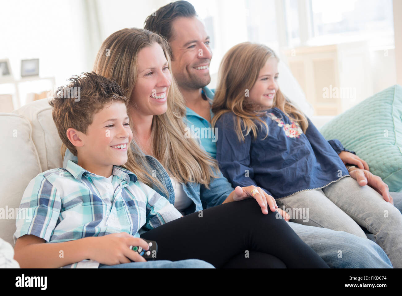 Famiglia con due bambini (6-7, 8-9) seduto sul divano Foto Stock