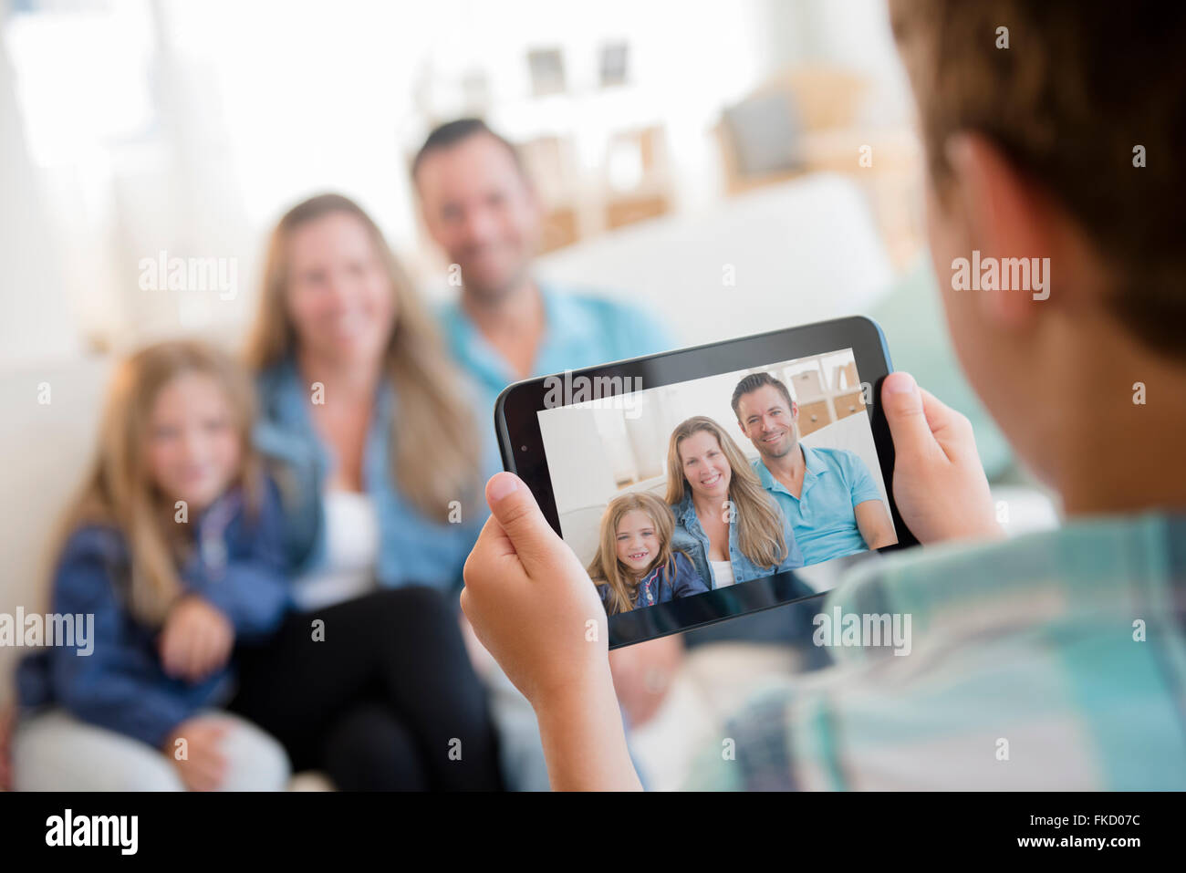Ragazzo (8-9) fotografare la famiglia con tavoletta digitale Foto Stock