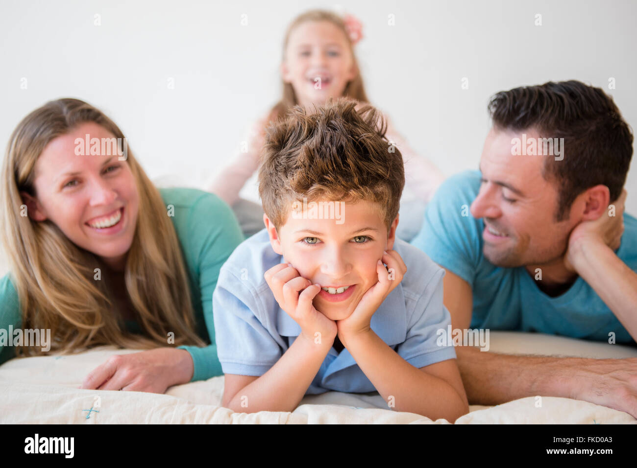 Famiglia con due bambini (6-7, 8-9) giacenti nel letto Foto Stock