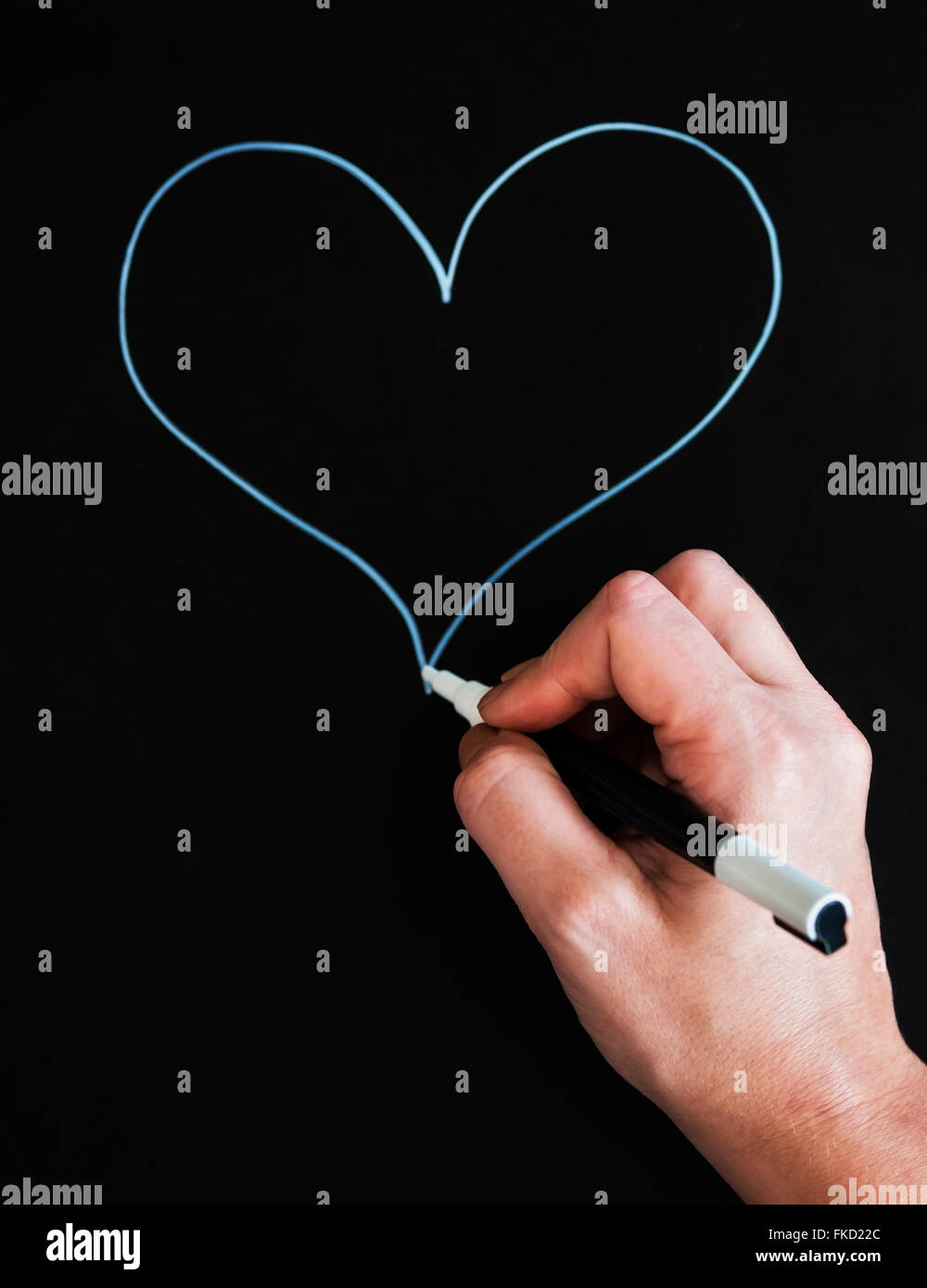 Mano d'uomo disegno forma di cuore su carta nera Foto Stock