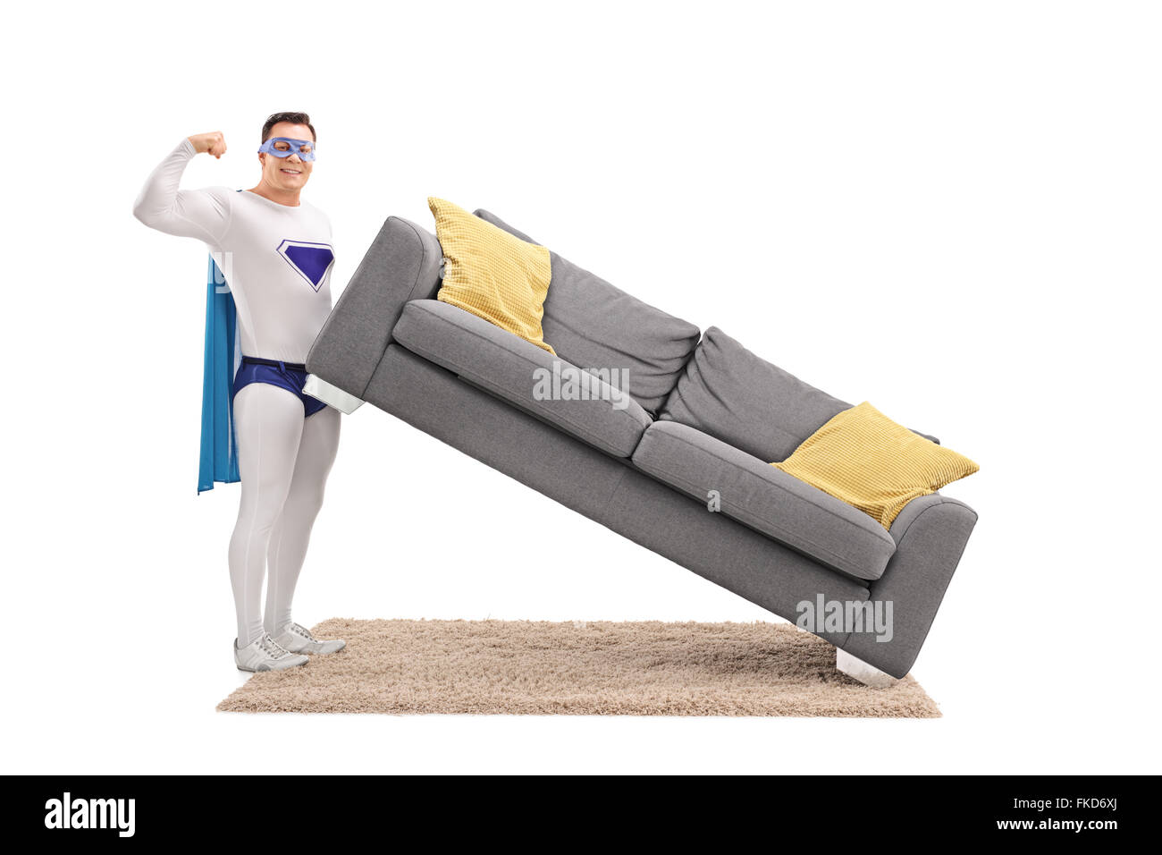 Giovane ragazzo in costume da supereroe sollevamento di un divano con una sola mano Foto Stock