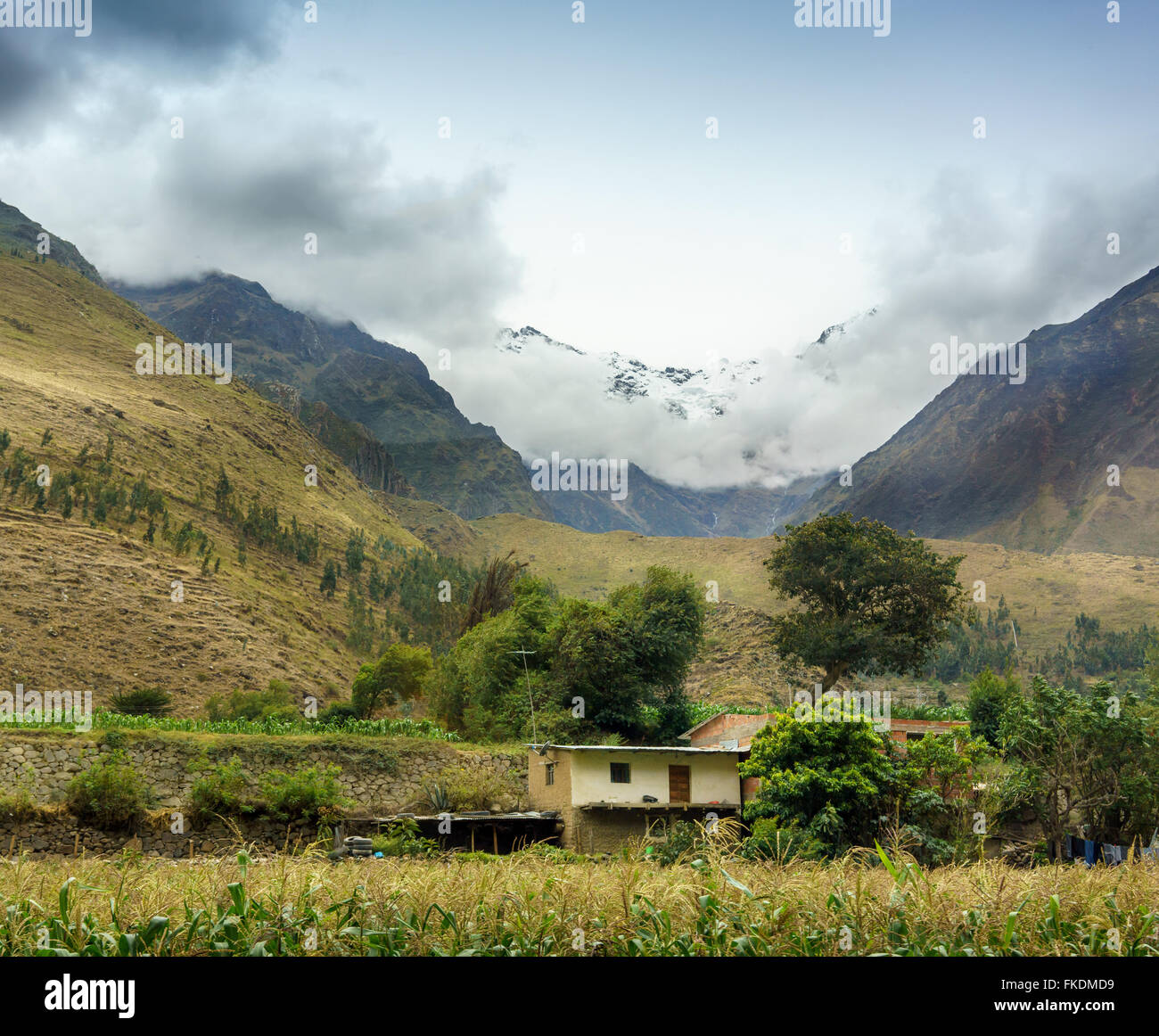 Villaggio sulla collina con snow-capped mountain in background contro sky, Cusco, Perù Foto Stock