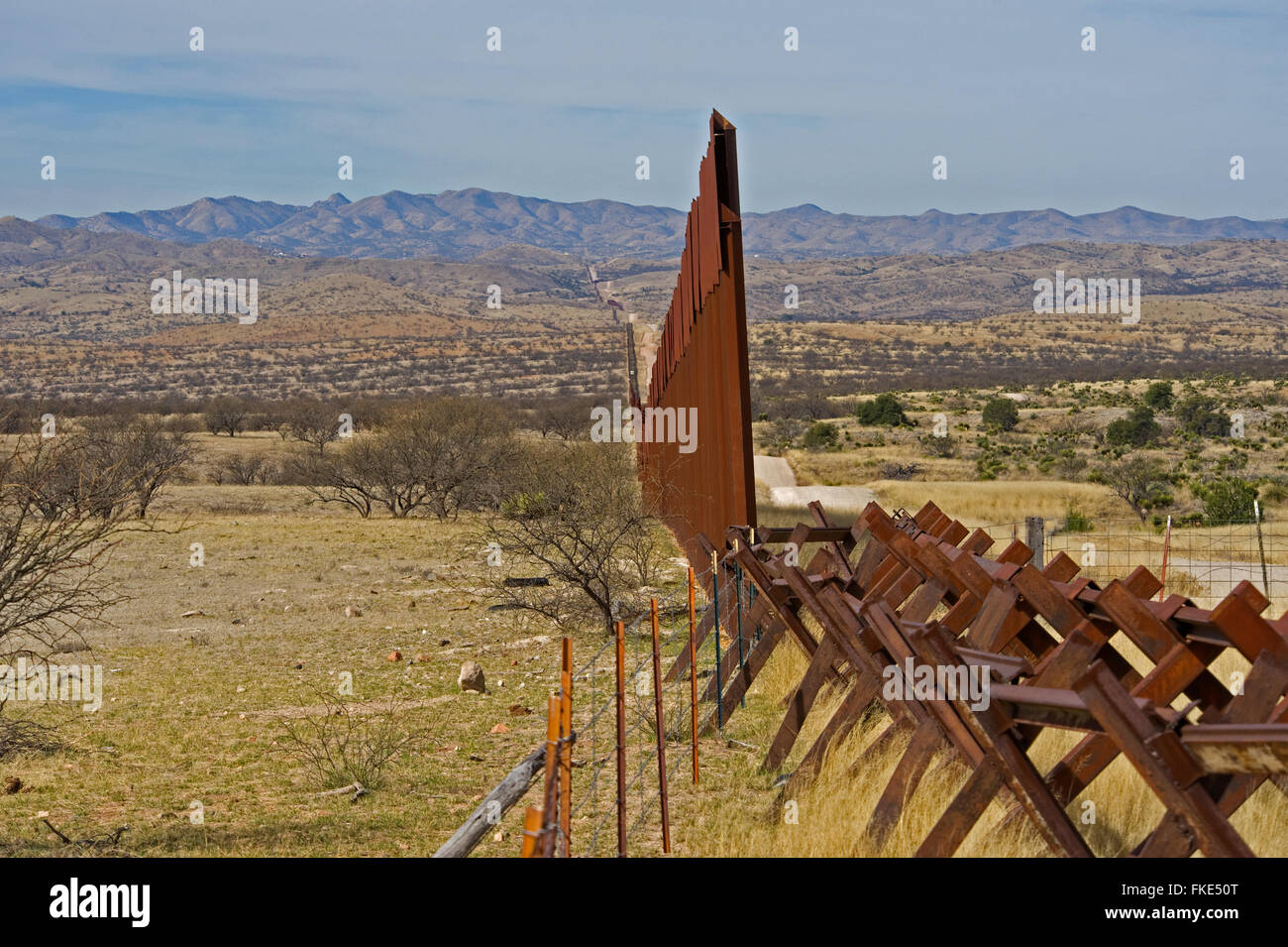 Noi recinzione di confine messicano di estremità laterali, con binari ferroviari che si estende la recinzione per impedire illegale di viaggio del veicolo NEGLI STATI UNITI. Landscap Foto Stock