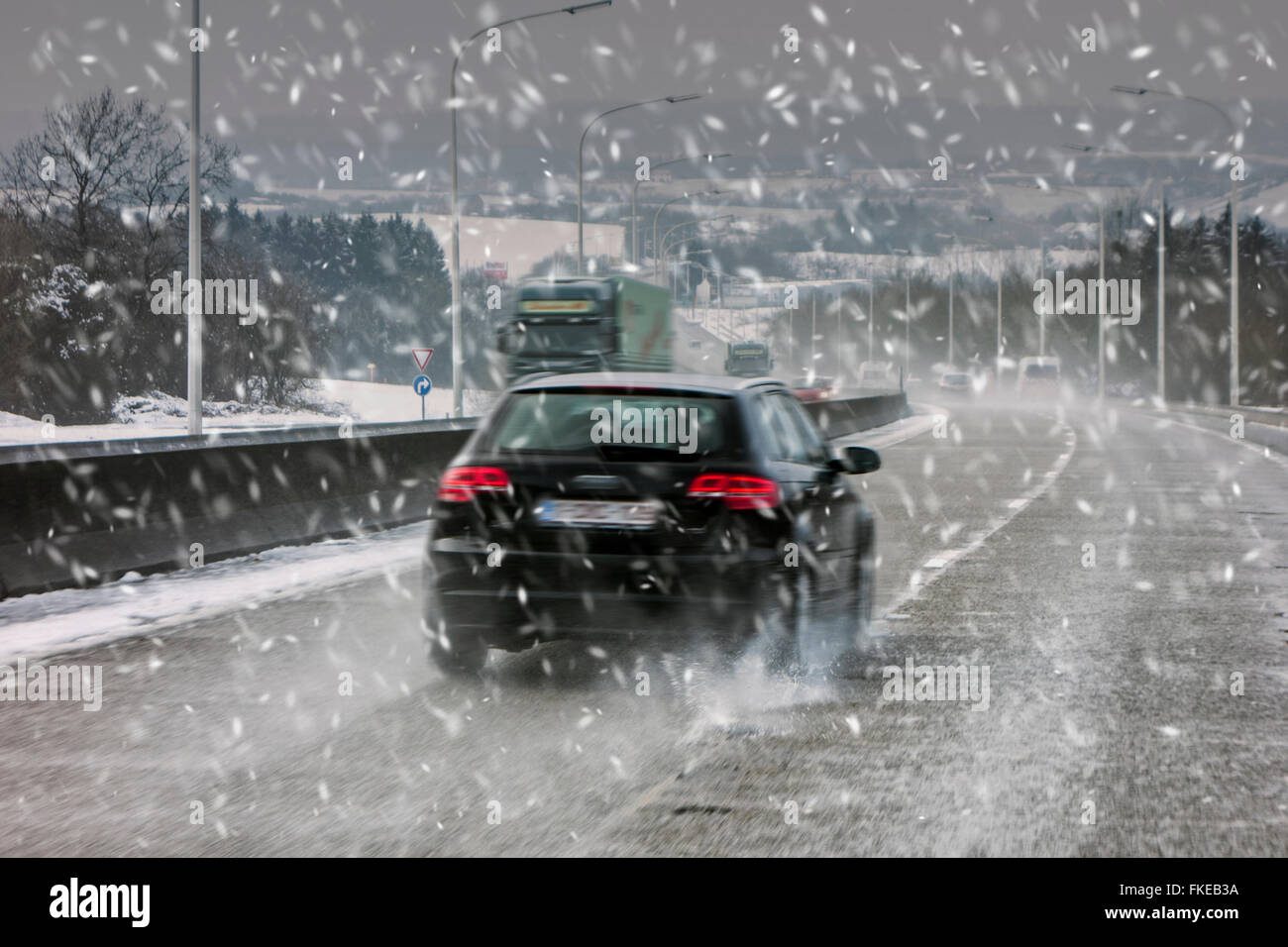 Vetture guida su autostrada sdrucciolevoli durante la neve pesante doccia causando pericolosi invernale sul bagnato in inverno / molla Foto Stock