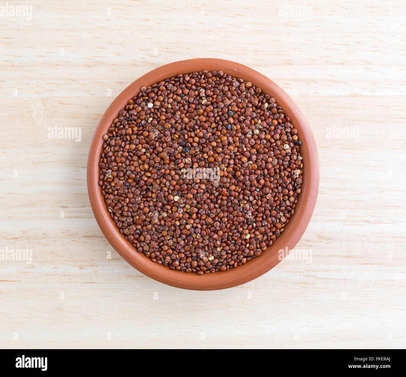 Vista dall'alto di una porzione di rosso la quinoa in una piccola ciotola su una tavola di legno top illuminato con luce naturale. Foto Stock