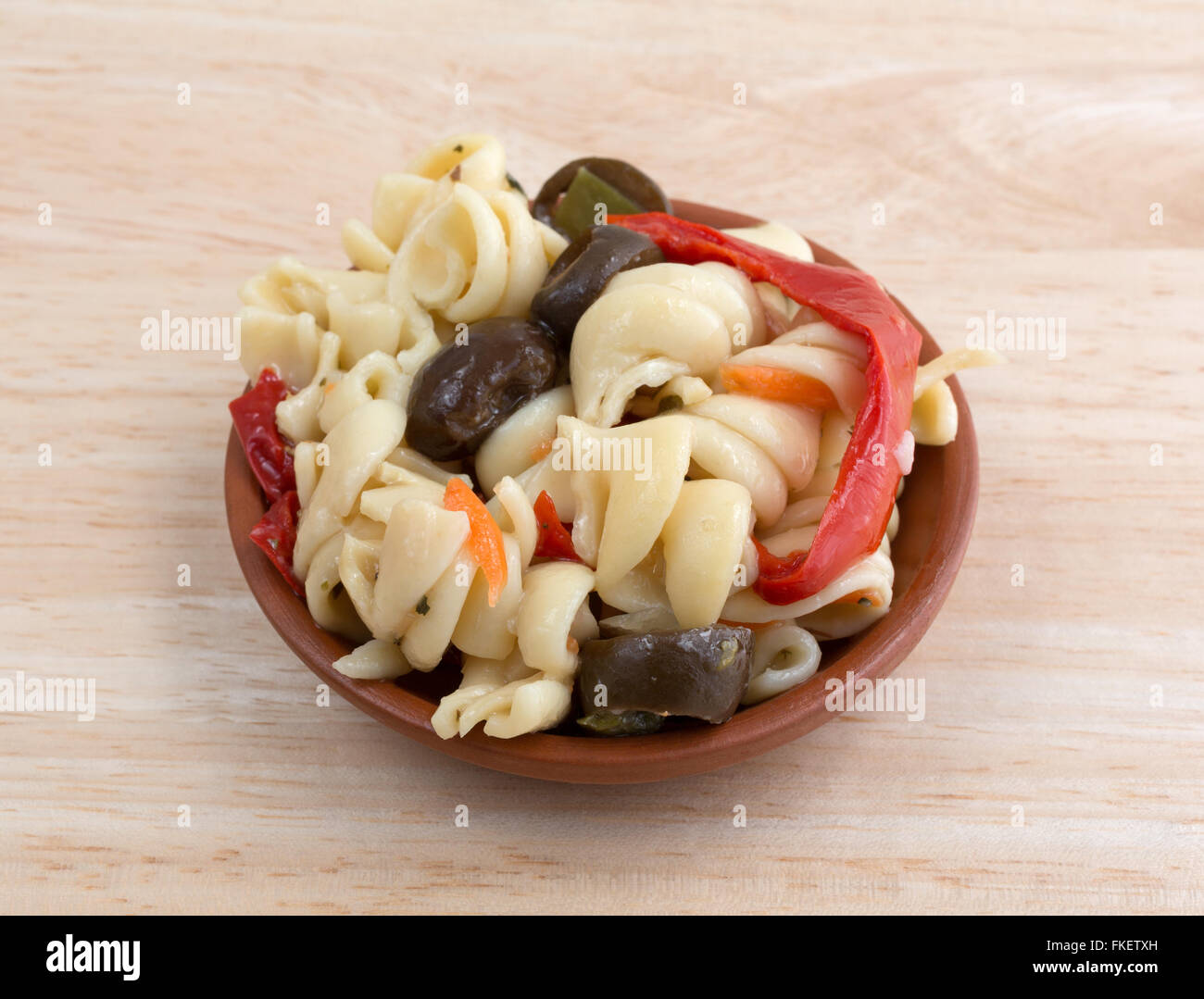 Un piccolo servizio di rotini insalata di pasta in un piccolo recipiente isolato su una tavola di legno alto. Foto Stock