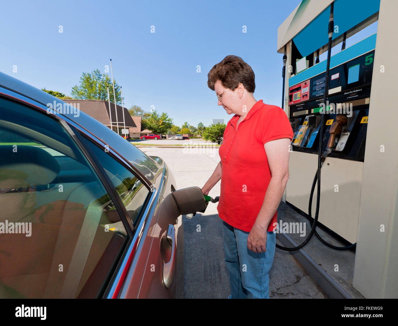 Donna di mezza età benzina di pompaggio Foto Stock
