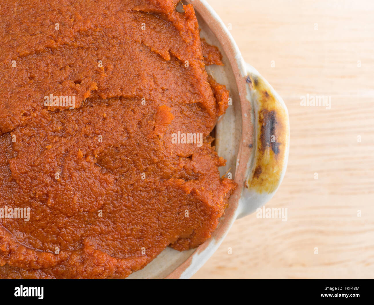 Top vista ravvicinata di una piccola ciotola riempita con curry rosso pasta su una tavola di legno alto. Foto Stock