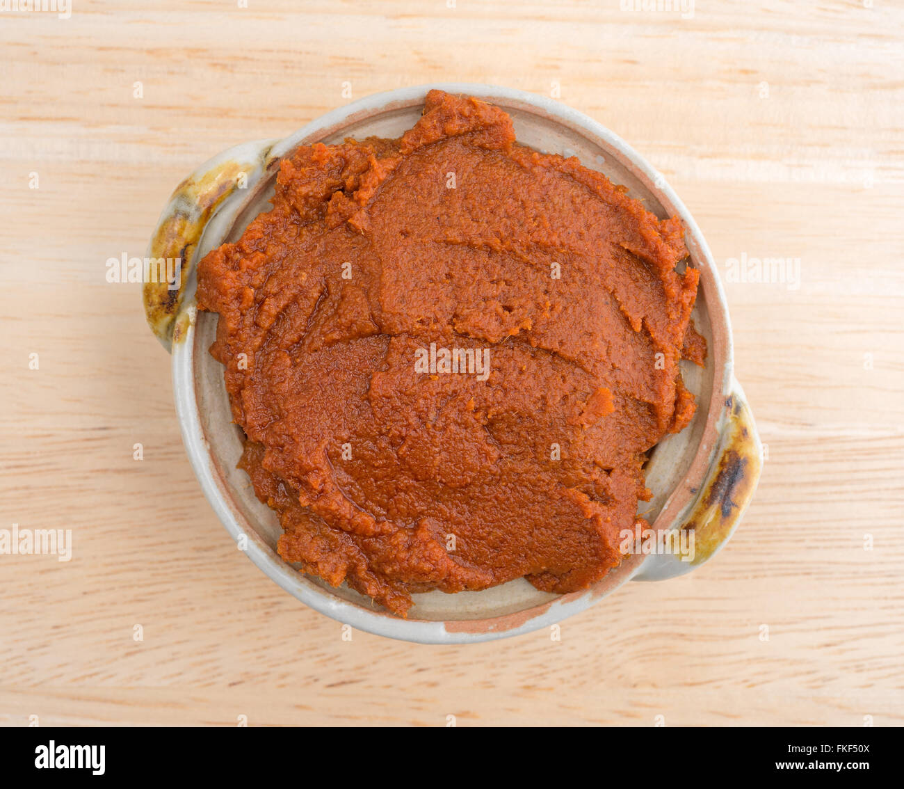 Vista dall'alto di una piccola ciotola riempita con curry rosso pasta su una tavola di legno alto. Foto Stock