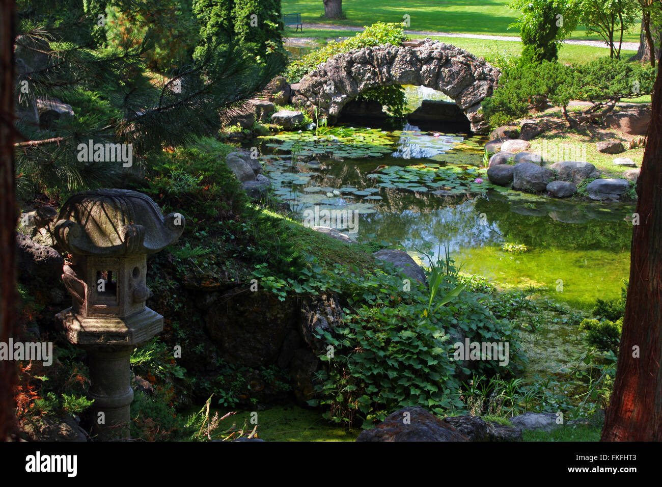 Canandaigua, New York, Sonnenberg giardini e Palazzo del parco statale. Un Jananese lanterna e arco in pietra ponte sopra un flusso, Foto Stock