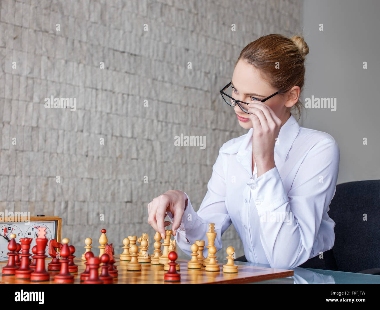 Smart donna bionda giocando a scacchi indoor Foto Stock