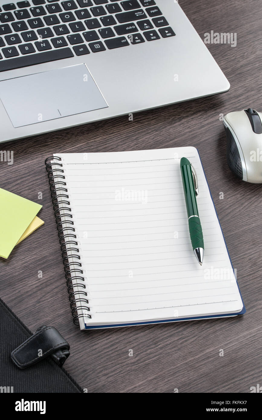 Laptop, notebook e penna con nota adesiva sulla scrivania Foto Stock