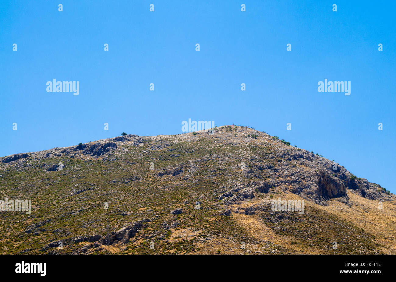 Top di deserto di montagna con alcuni vegetazione contro il cielo blu. Foto Stock