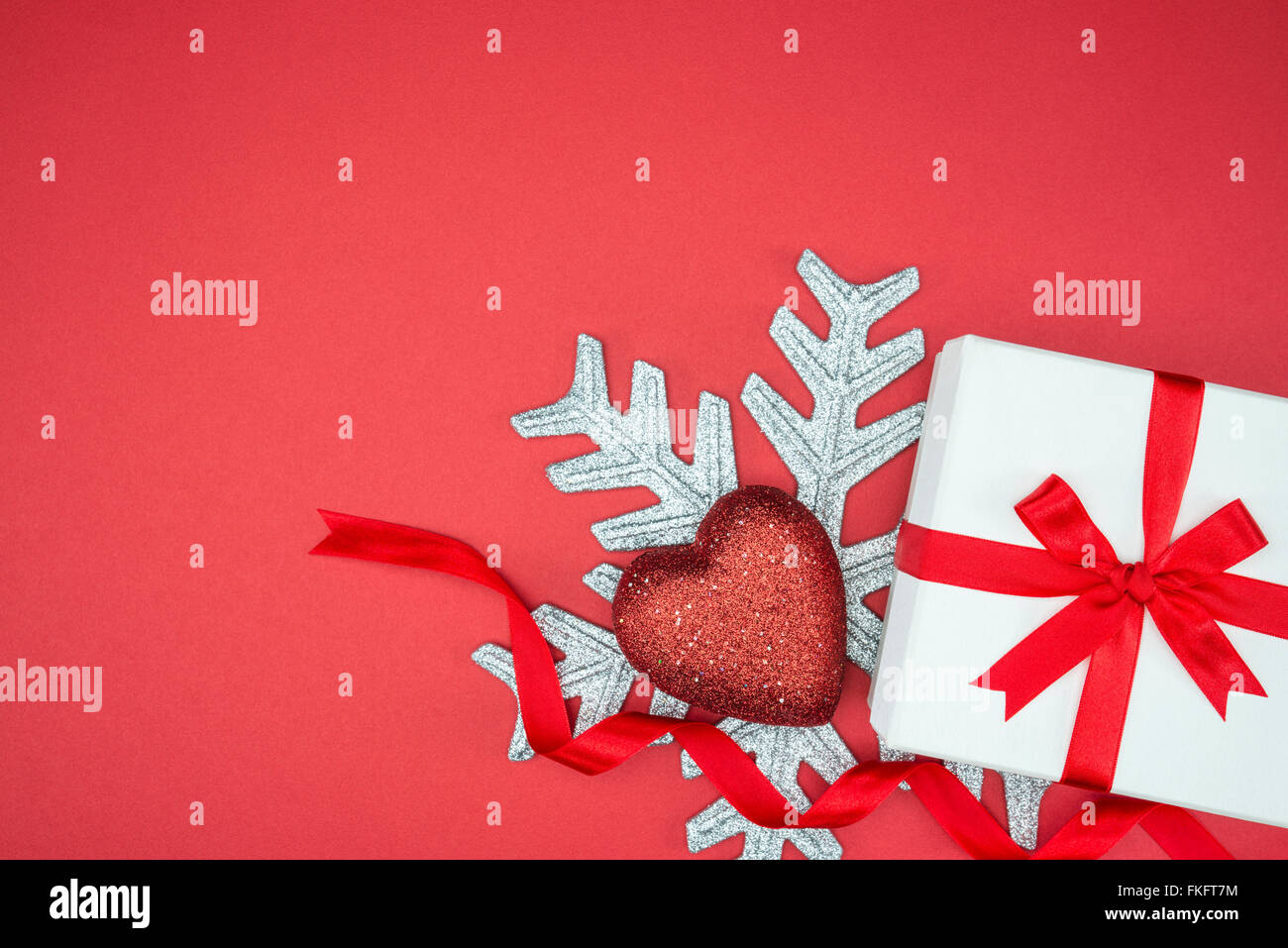 Elegante confezione regalo per le feste evento wrap seta cuore fiocco di neve su sfondo rosso isolato Foto Stock