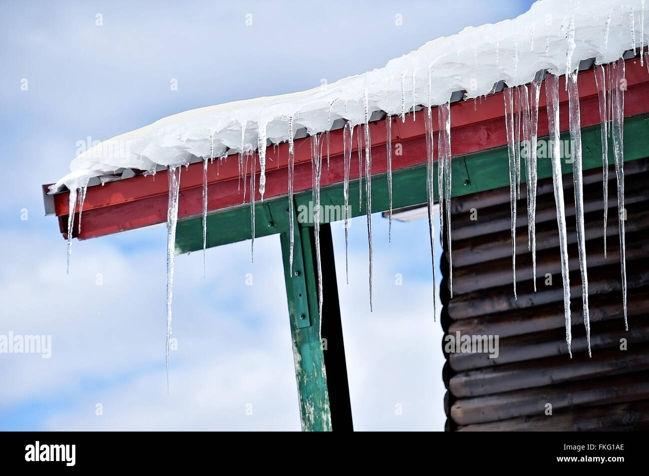 Inverno dettaglio con fusione ghiaccioli sul tetto di chalet in legno Foto Stock