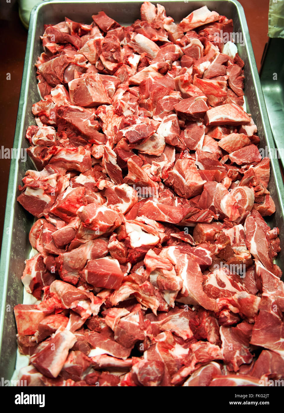 Vista ravvicinata nel tempo vassoio metallico riempito con decine di materie, recentemente trasformati tritare la carne di maiale bit in impianto per la trasformazione di carni Foto Stock