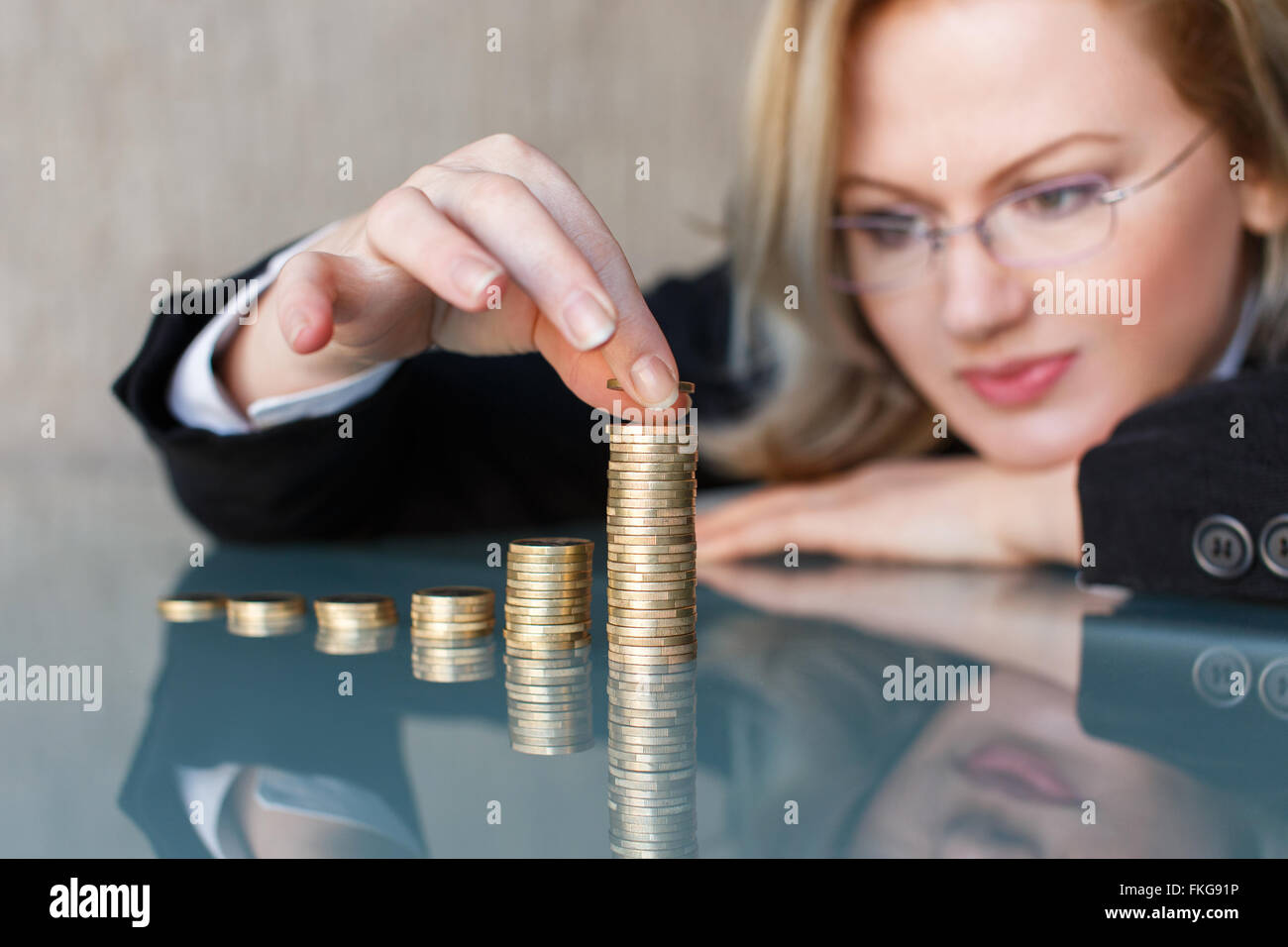 La bionda imprenditrice nel edificio di occhiali in crescita di euro colonne, risparmiando denaro concetto. Foto Stock