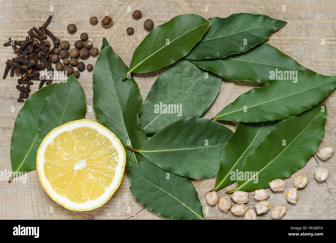 La metà di un limone, la foglia di alloro, spezie, giacente sulla vecchia scheda Foto Stock