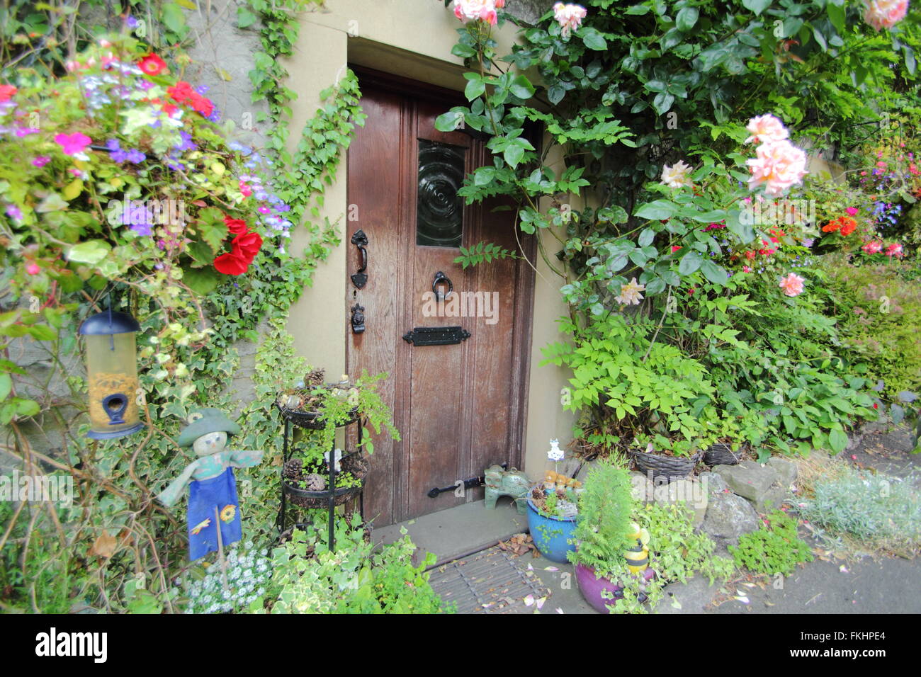 Rose e fiori estivi crescere intorno alla porta anteriore di un tradizionale cottage in pietra nel Peak District, DERBYSHIRE REGNO UNITO Inghilterra Foto Stock