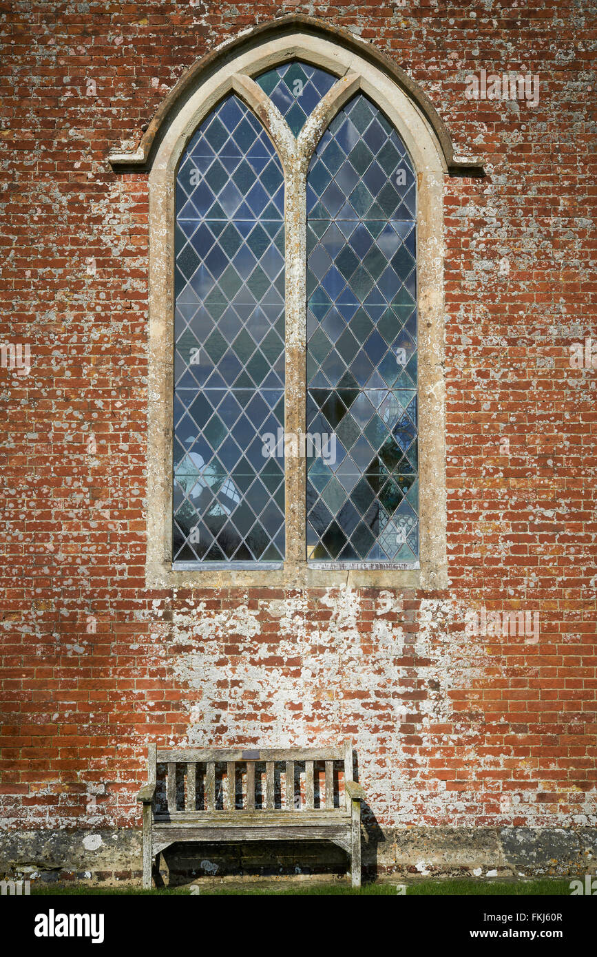 Una panca in legno davanti a una chiesa con piombo finestra Foto Stock