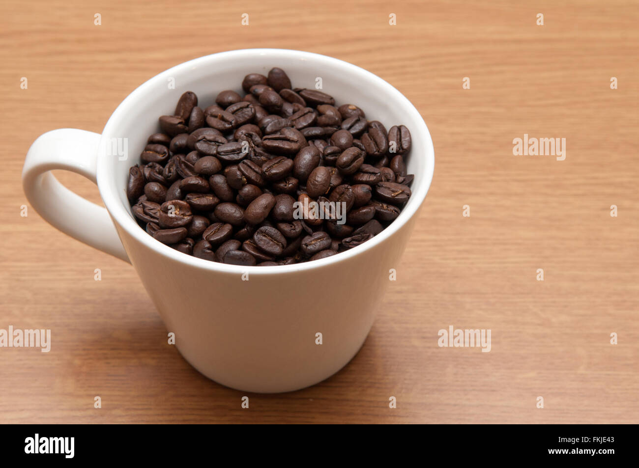 Di sapore molto forte i chicchi di caffè in una normale tazza bianca Foto Stock