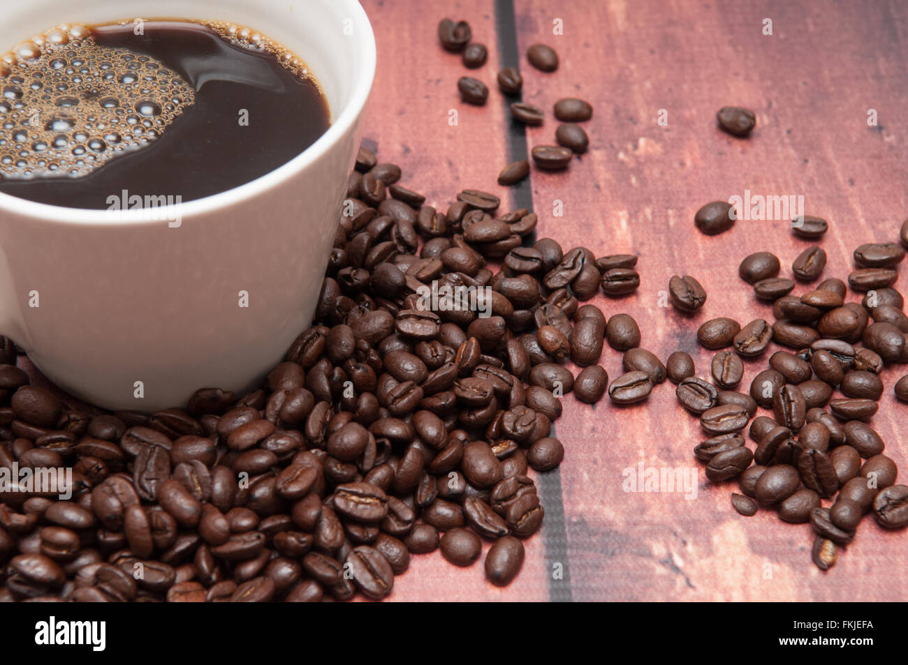 Di sapore molto forte i chicchi di caffè in una normale tazza bianca Foto Stock
