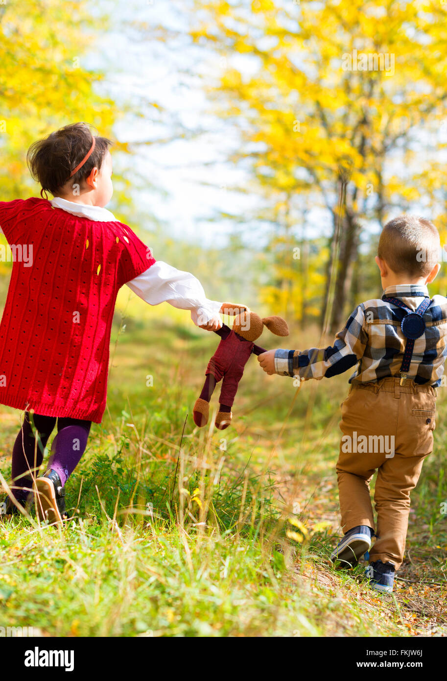 Bambina e ragazzo a piedi con il loro giocattolo preferito Foto Stock