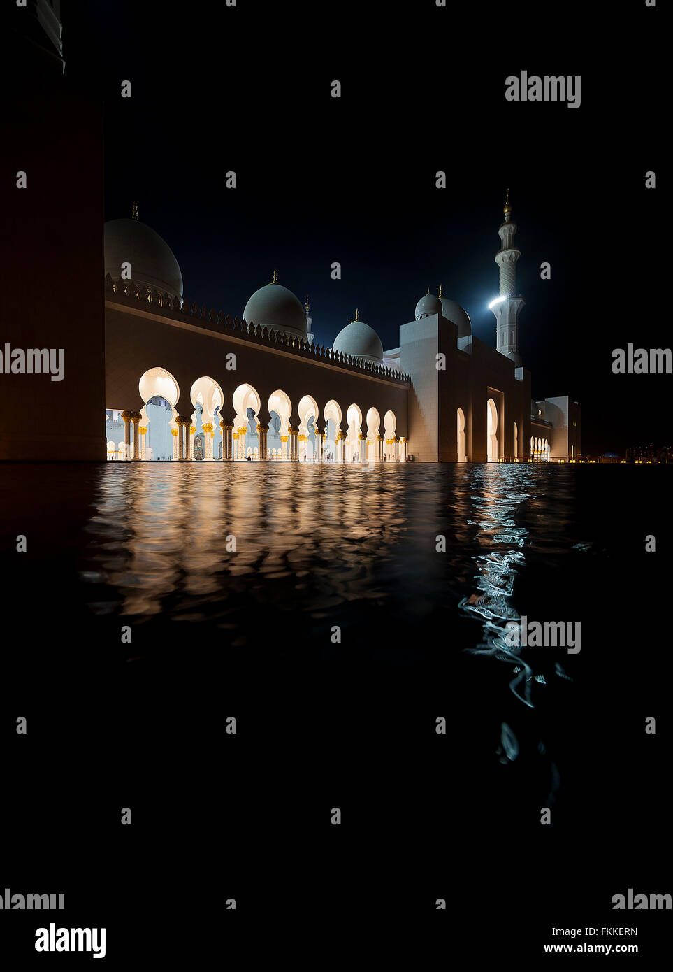 Una vista di archi e acqua in un edificio moderno ad Abu Dhabi, chiamato lo sceicco Zayed Grande Moschea, scattata di notte. Foto Stock