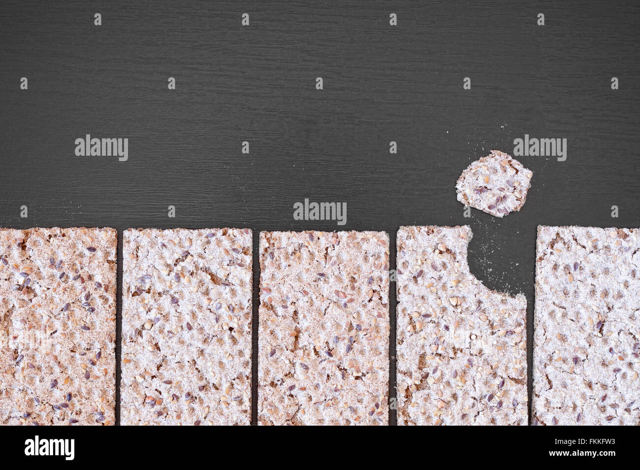 Vista superiore del grano intero croccante crackers con semi su un tavoli in legno nero. Foto Stock