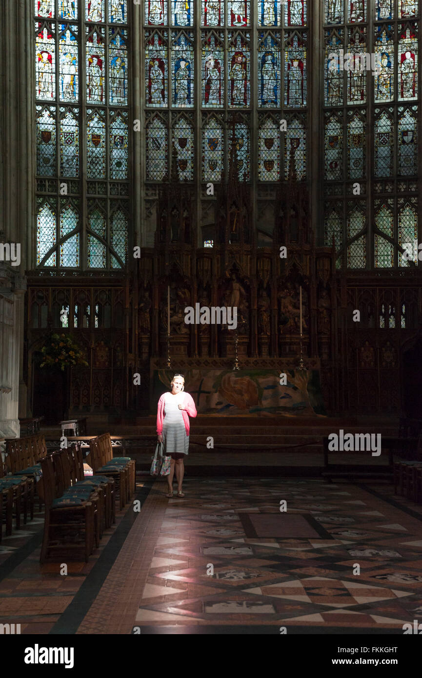 Una donna si trova in un raggio di luce all'interno della cattedrale di Gloucester , Gloucestershire , Inghilterra , Inghilterra , Regno Unito Foto Stock