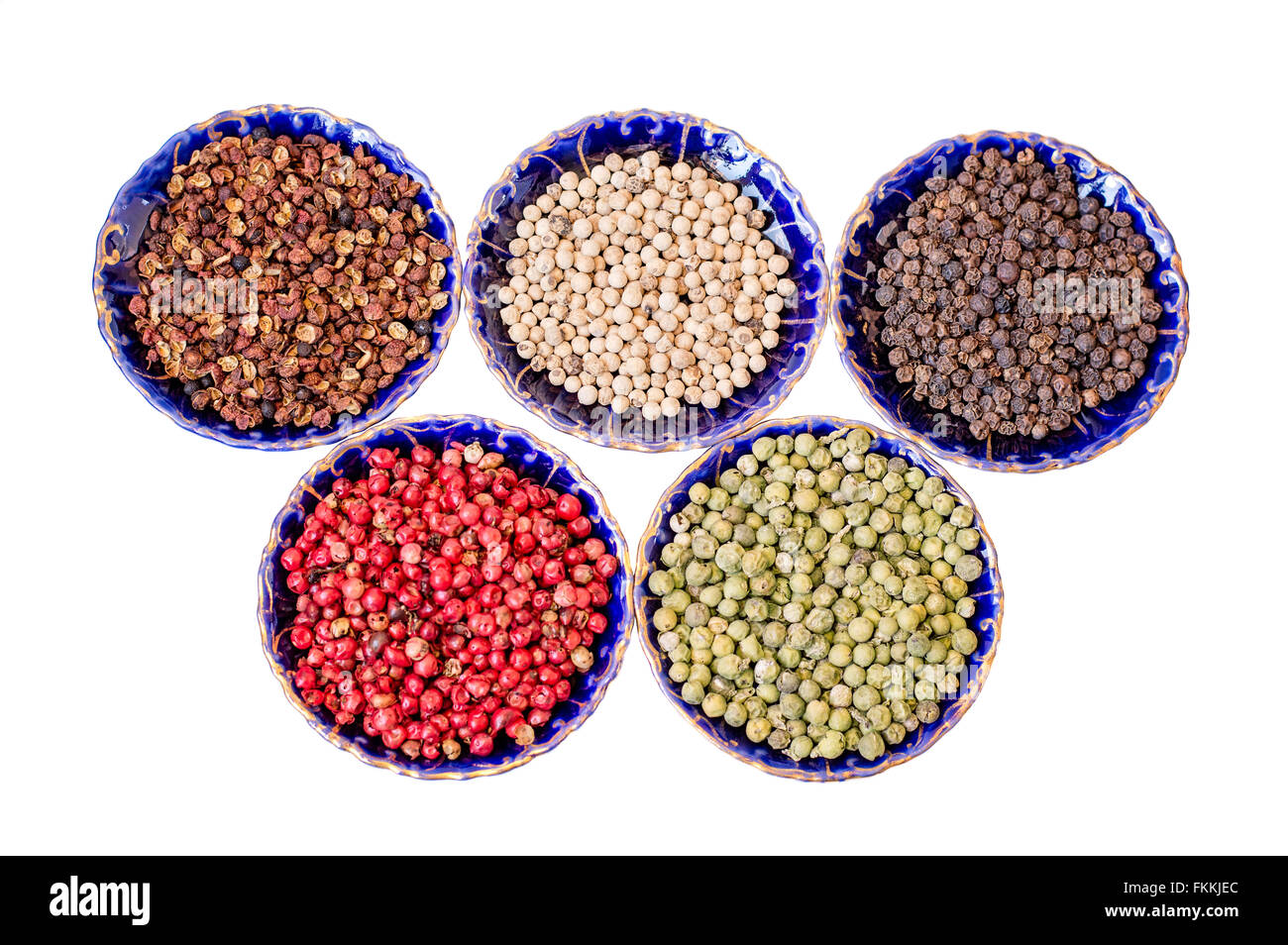 Sichuan, bianco, rosso, verde, grani di pepe nero in blu vintage piattini in CERAMICA isolata su bianco. Foto Stock