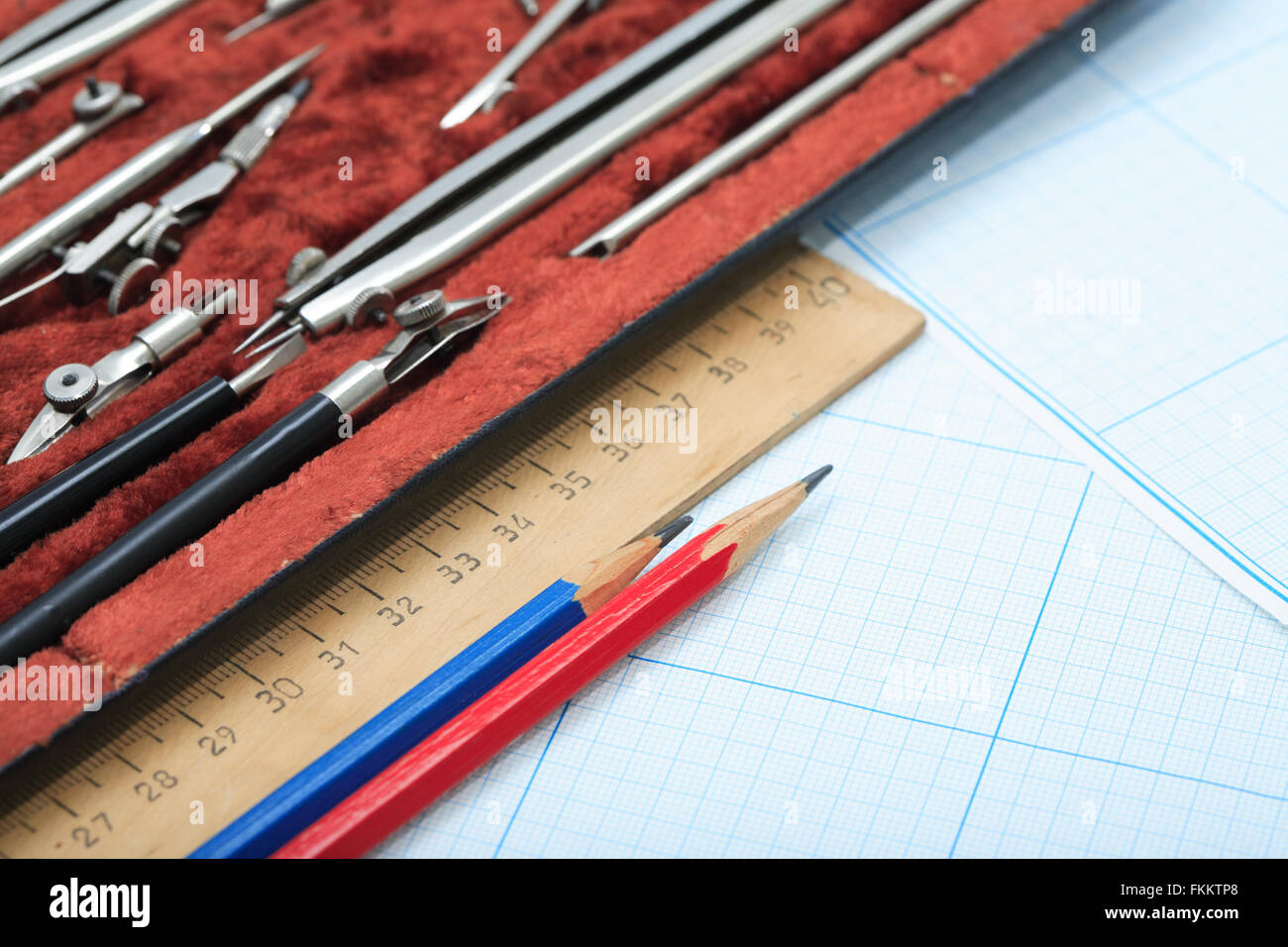 Set di strumenti di disegno nella casella e un righello su un foglio di carta millimetrata Foto Stock