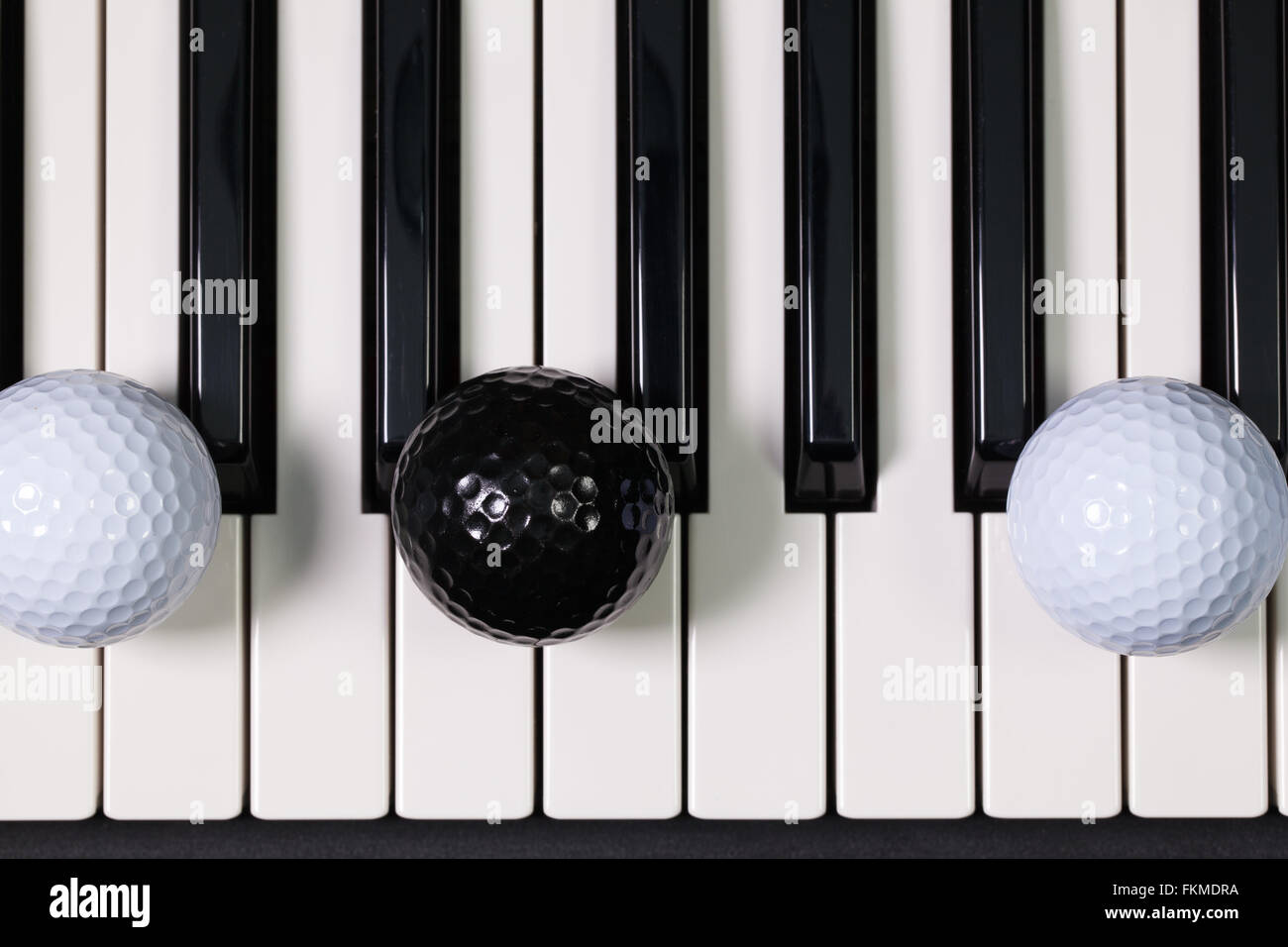 Virtuosi di gioco - Una tastiera di pianoforte e differenti palline da golf e tee di legno Foto Stock