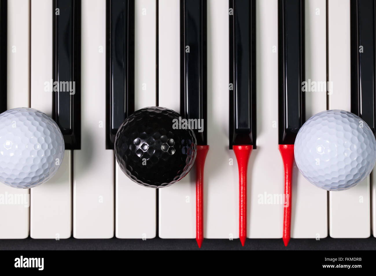 Virtuosi di gioco - Una tastiera di pianoforte e differenti palline da golf e tee di legno Foto Stock