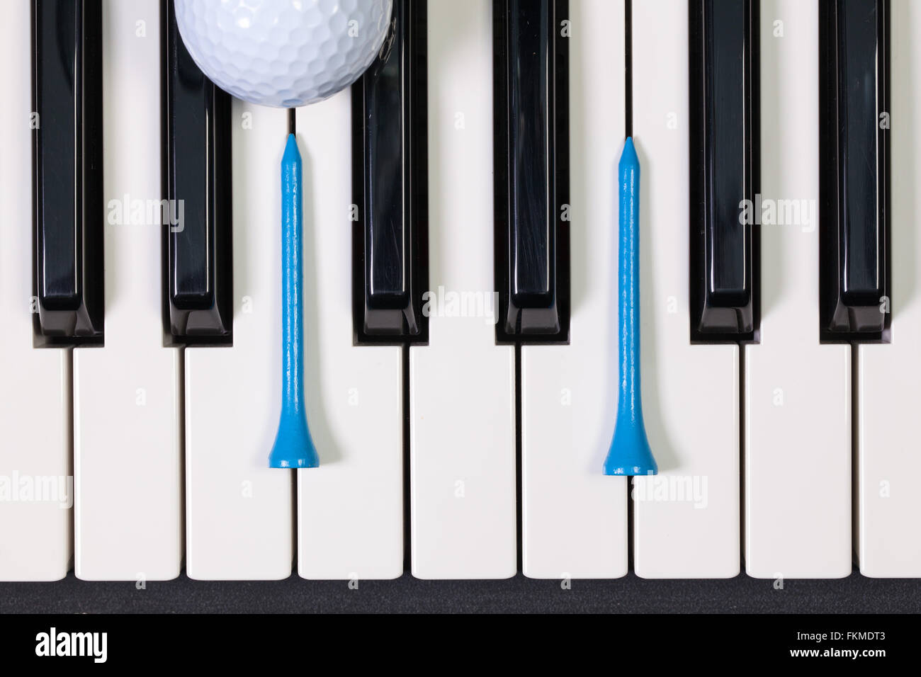 Virtuosi di gioco - Una tastiera di pianoforte e differenti palline da golf e tee di legno Foto Stock