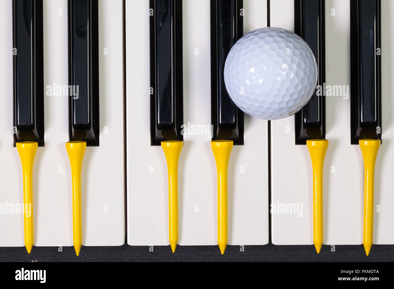 Virtuosi di gioco - Una tastiera di pianoforte e differenti palline da golf e tee di legno Foto Stock