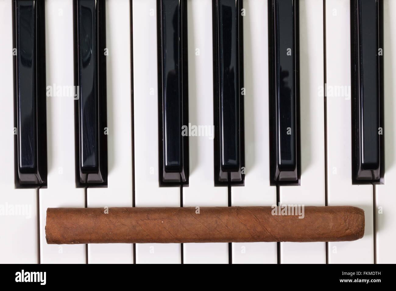 Dettaglio della tastiera di pianoforte e sigari di lusso Foto Stock