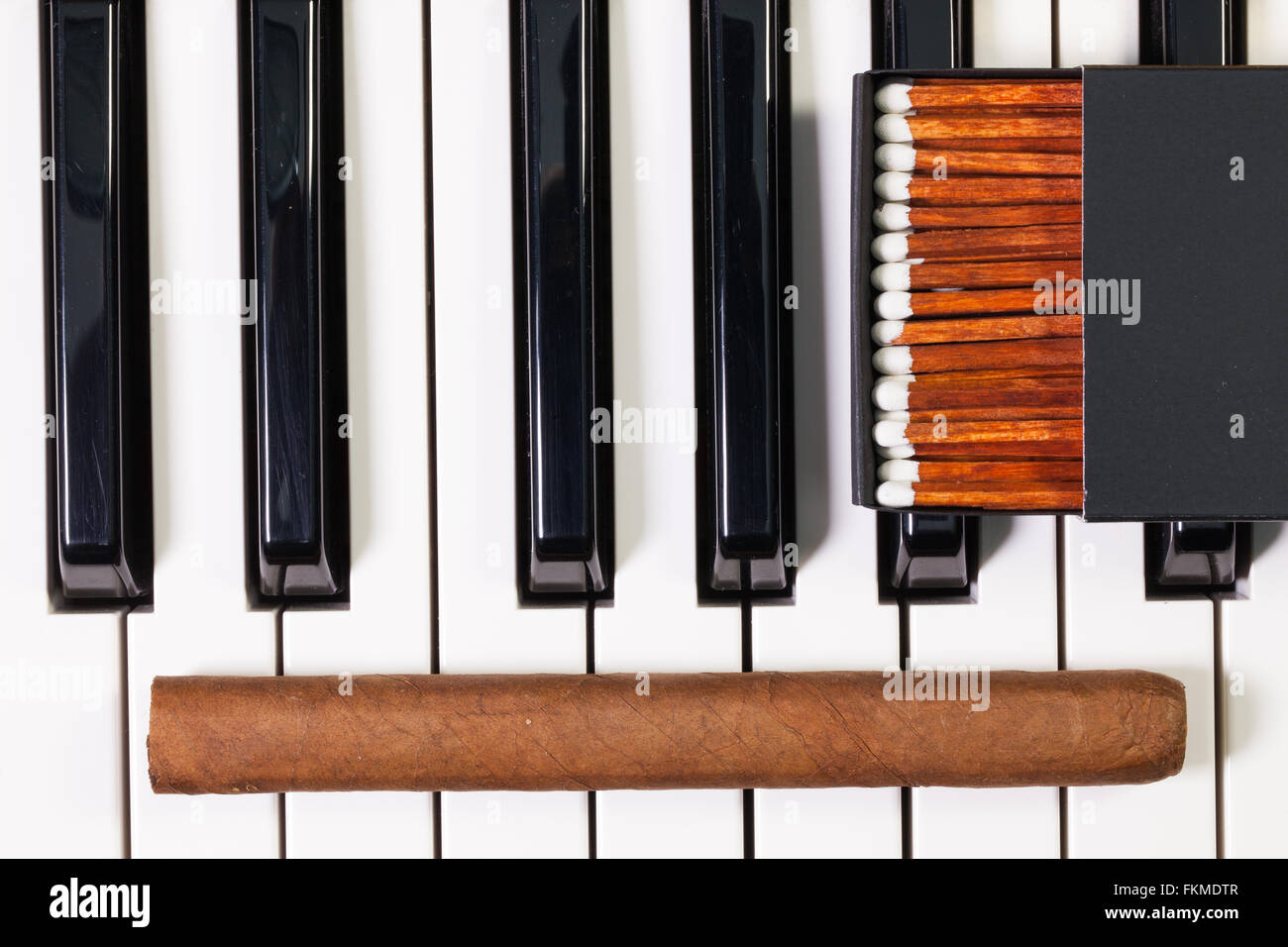 Dettaglio della tastiera di pianoforte e sigari di lusso Foto Stock