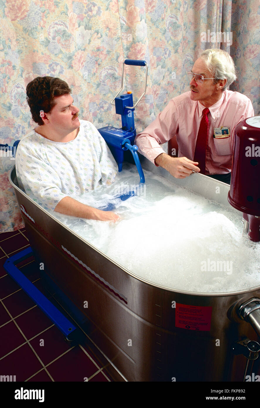 Paziente di sesso maschile in vasca idromassaggio per la terapia fisica Foto Stock