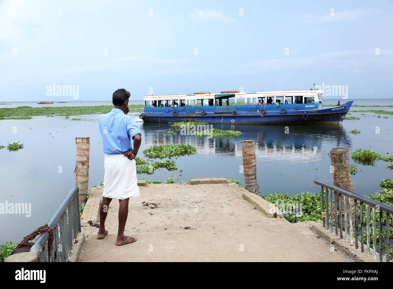 Il Kerala Backwaters, un uomo appena perso un trasporto pubblico in barca e in attesa per il prossimo viaggio a Kerala Foto Stock